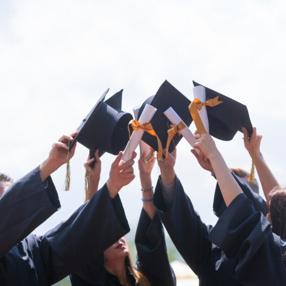 Graduates holding up their graduation caps.