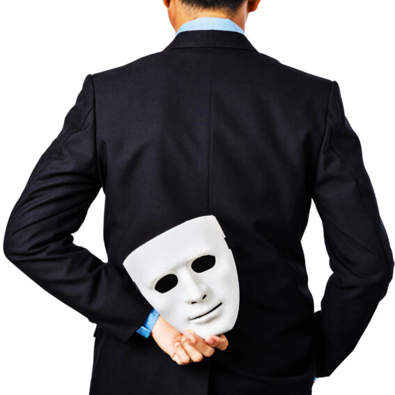 Fraudster holding a mask behind their back.
