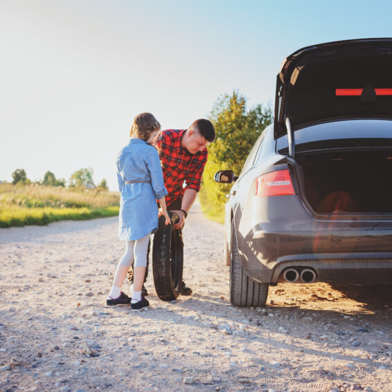 Father and daughter changing a tire on a vehicle.